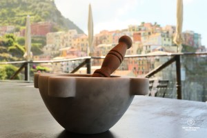 Carrara marble mortar and pestle with the village of Manarola, Cinque Terre, in the background for the pesto workshop at Nessun Dorma