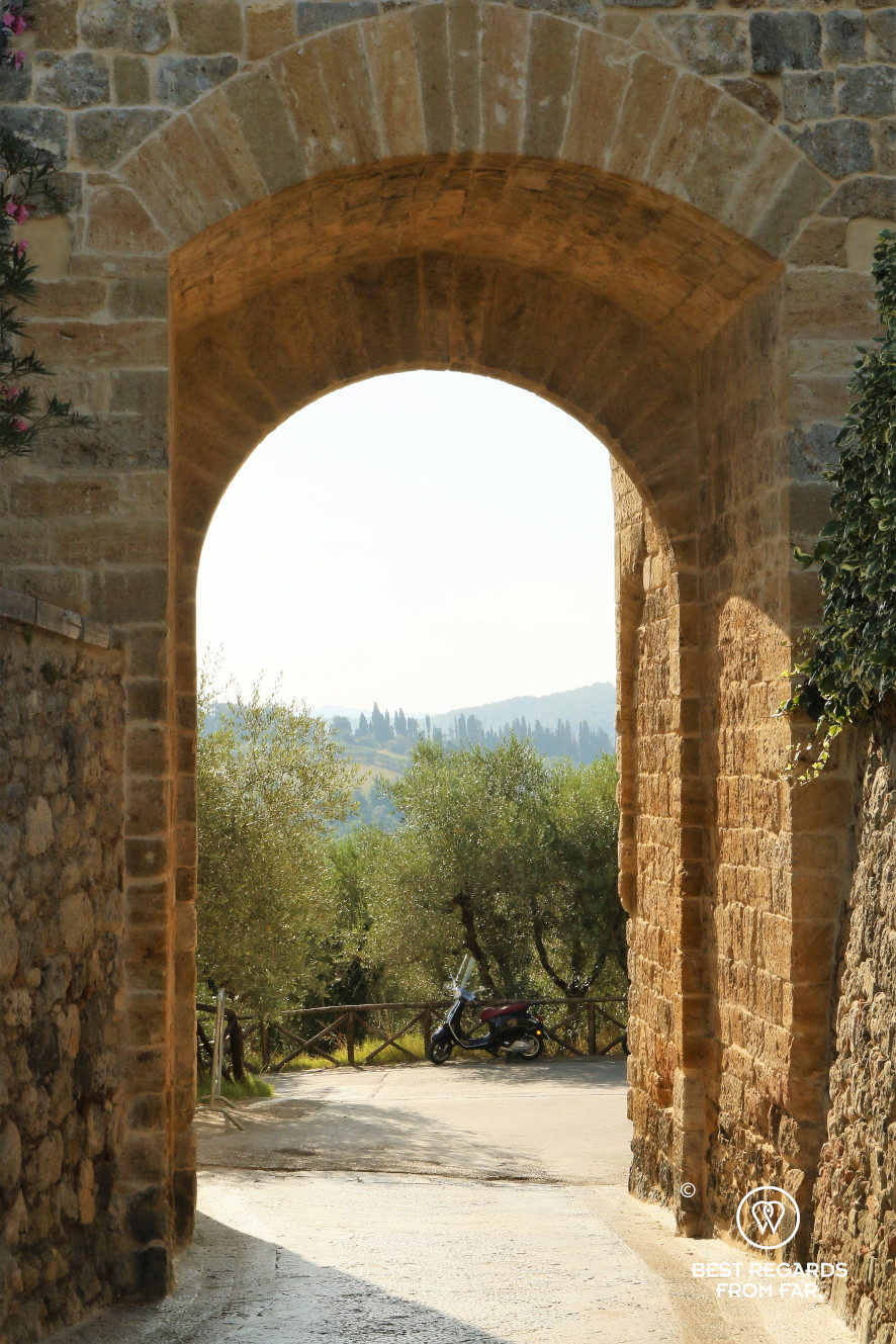 One of the gates of Monteriggioni framing a Vespa scooter, Italy
