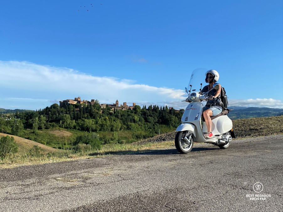 Woman riding a white Vespa scooter by Certaldo, Tuscany, Italy