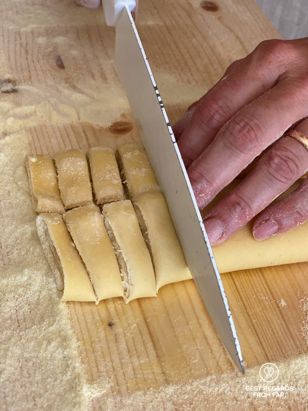 Fresh tagliatelle being cut with a large knife