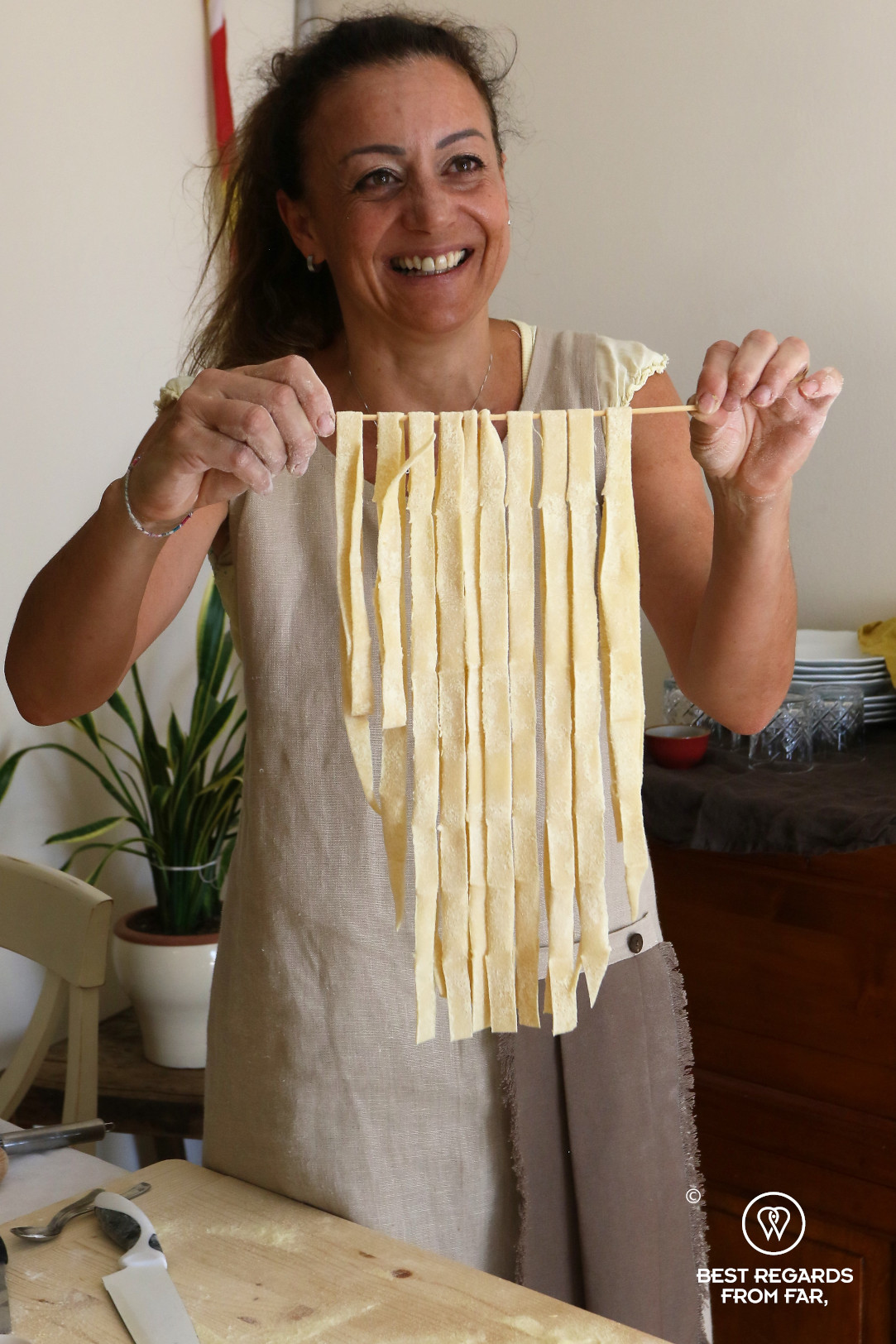 Woman holding up freshly made tagliatelle pasta during a cooking course