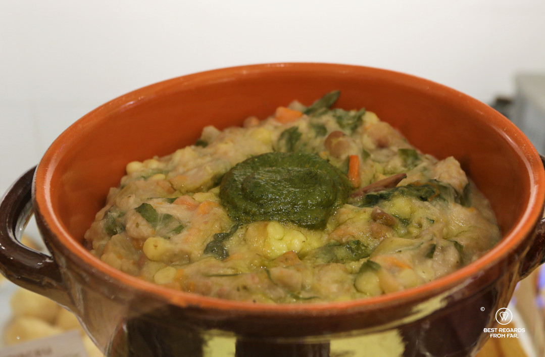A bowl filled with a thick minestrone soup and pesto on top