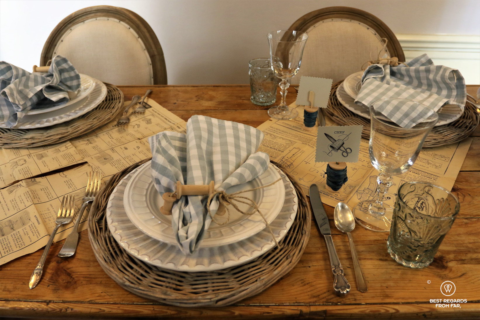 Wooden table set for three people, plates, napkins and glasses.