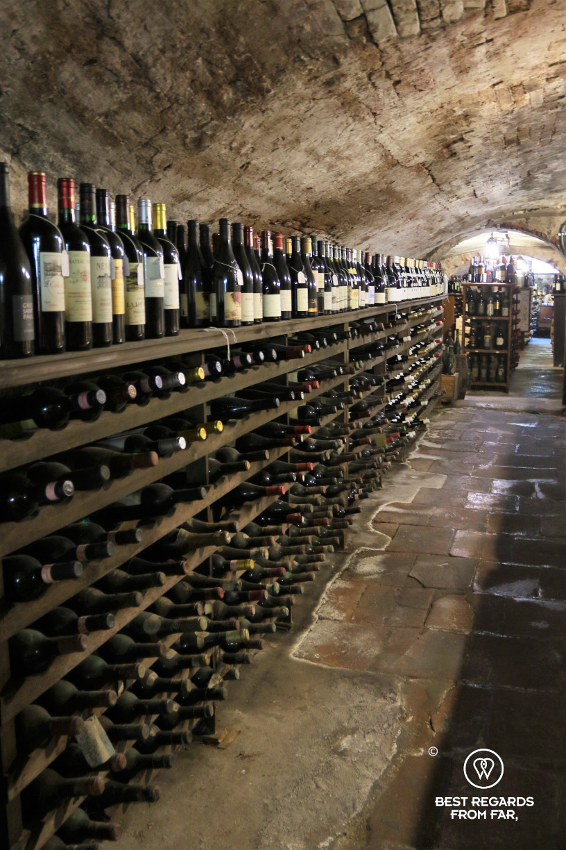 Long rown of bottles of wine stored in a vaulted cellar from Roman times in Italy.