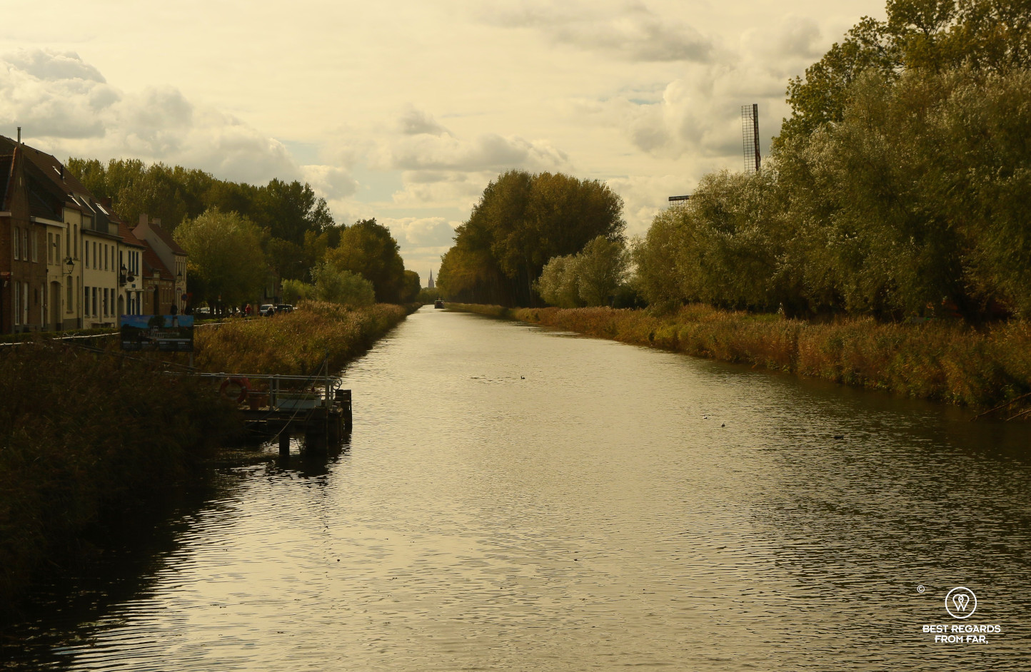 Canal in with a windmill next to it in Belgium