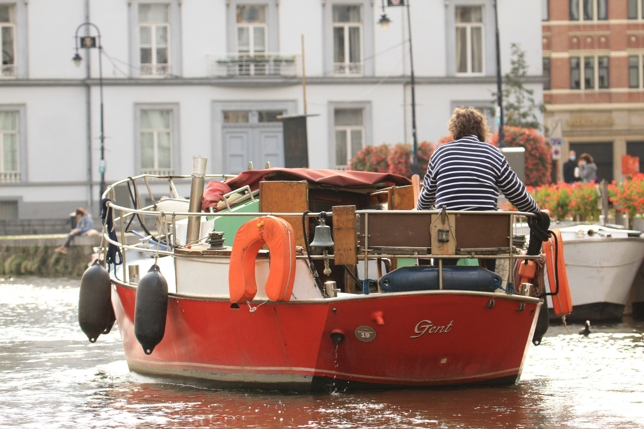 Man on a small red boat in Ghent, Belgium