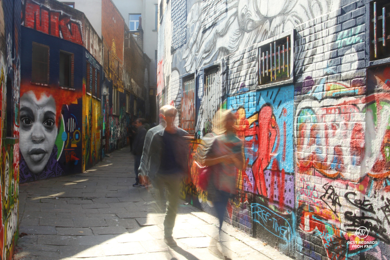 Two people walking through the colourful graffiti street in Ghen, Belgium