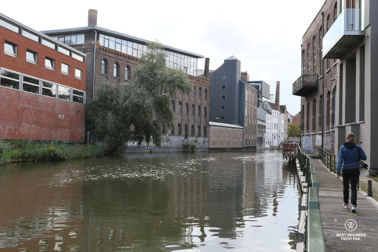 Woman walking along a tow path discovering the industrial side of Ghent, Belgium