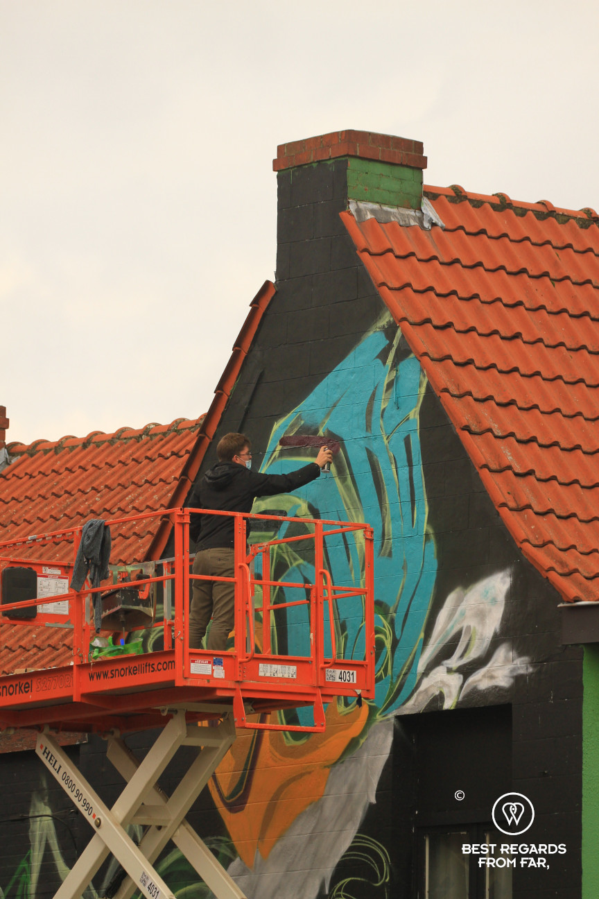 Street artist at work with graffiti on a facade in Ghent, Belgium