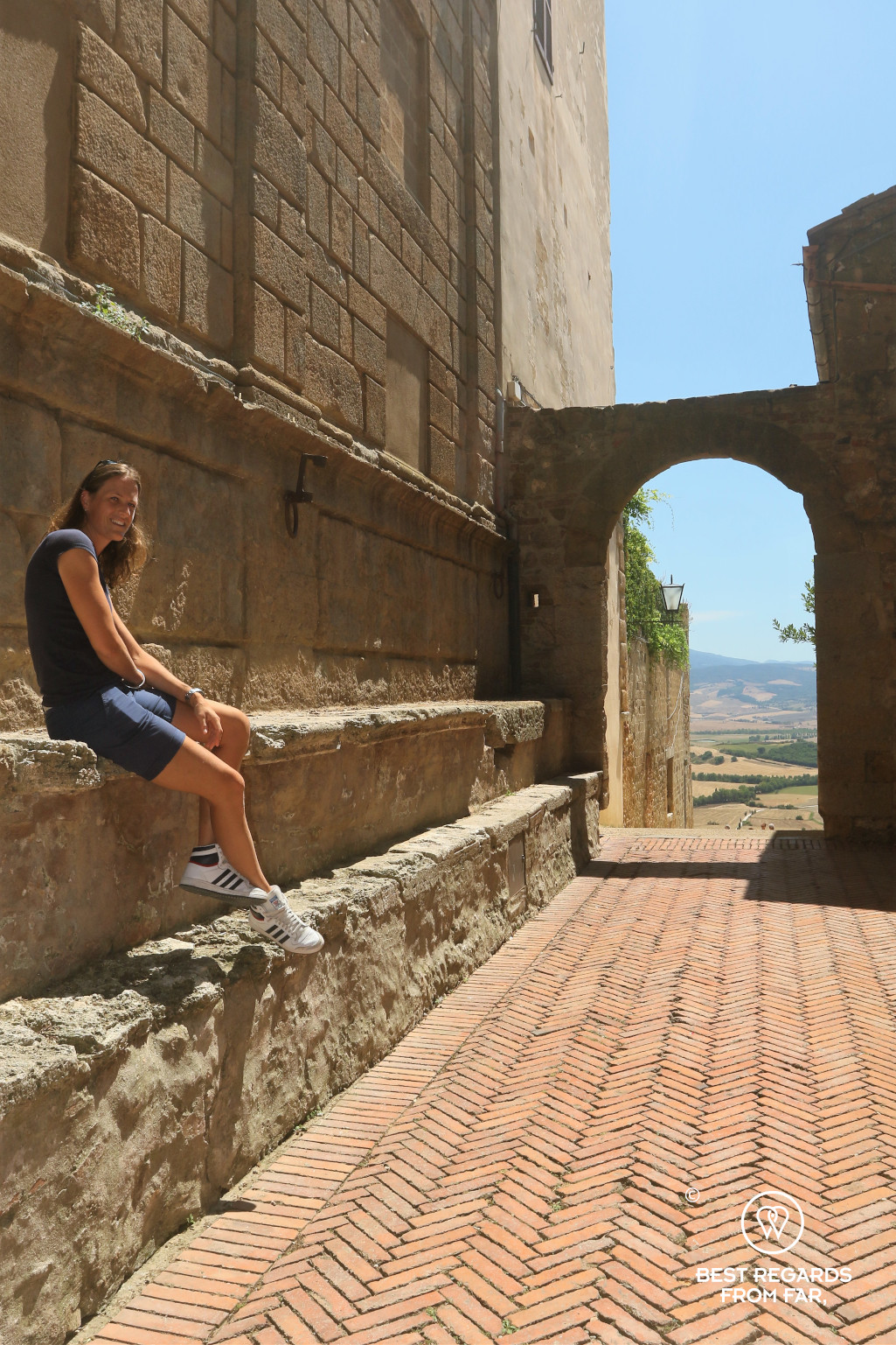 Woman sitting on a medieval wall with a nice view in Italy