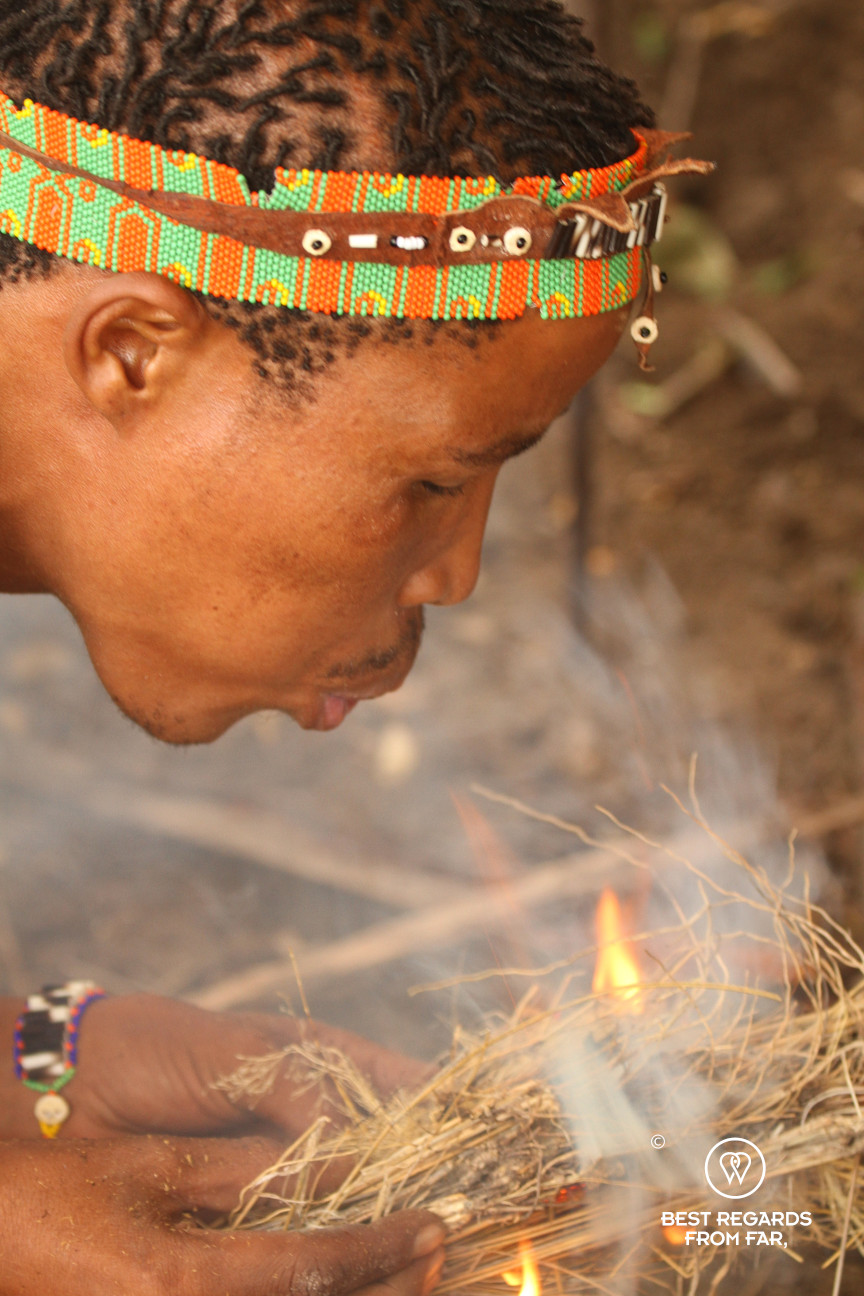 San man blowing on a fire, Botswana.