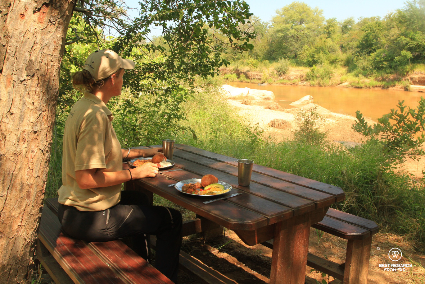 Person having lunch on a picnic table in bush camp overlooking the Selati River, South Africa