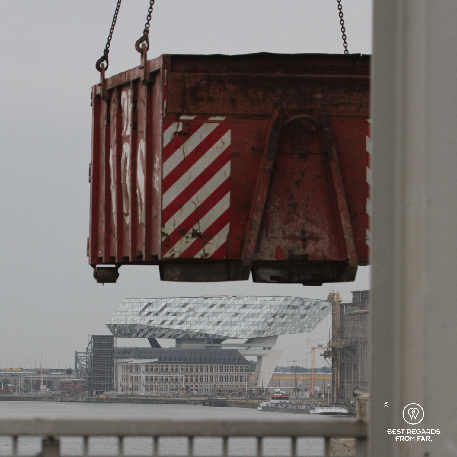 Iconic Port House of Antwerp seen from the harbour and framed by a red container