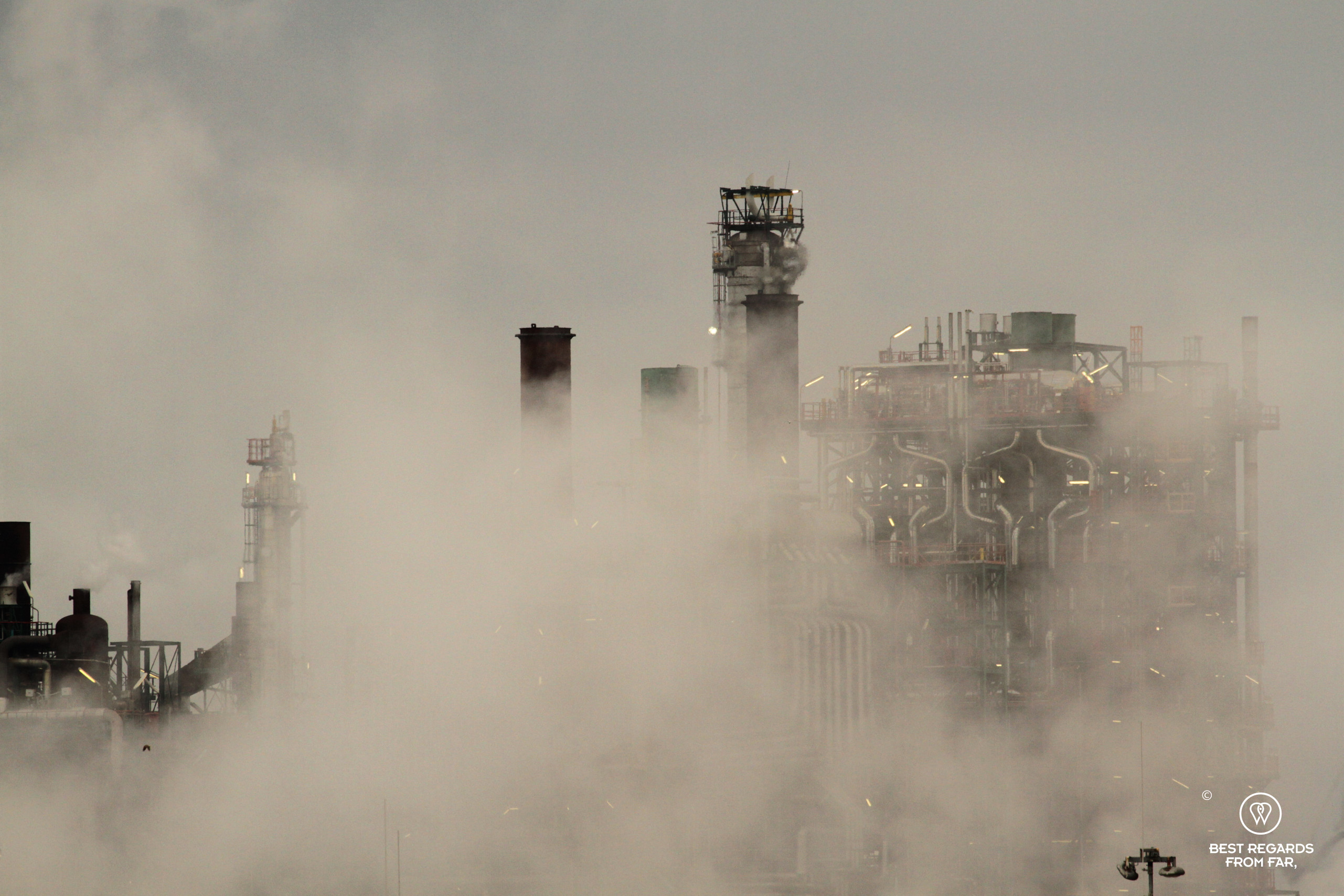 Lit refinery amidst exhaust smoke in the harbour of Antwerp, Belgium