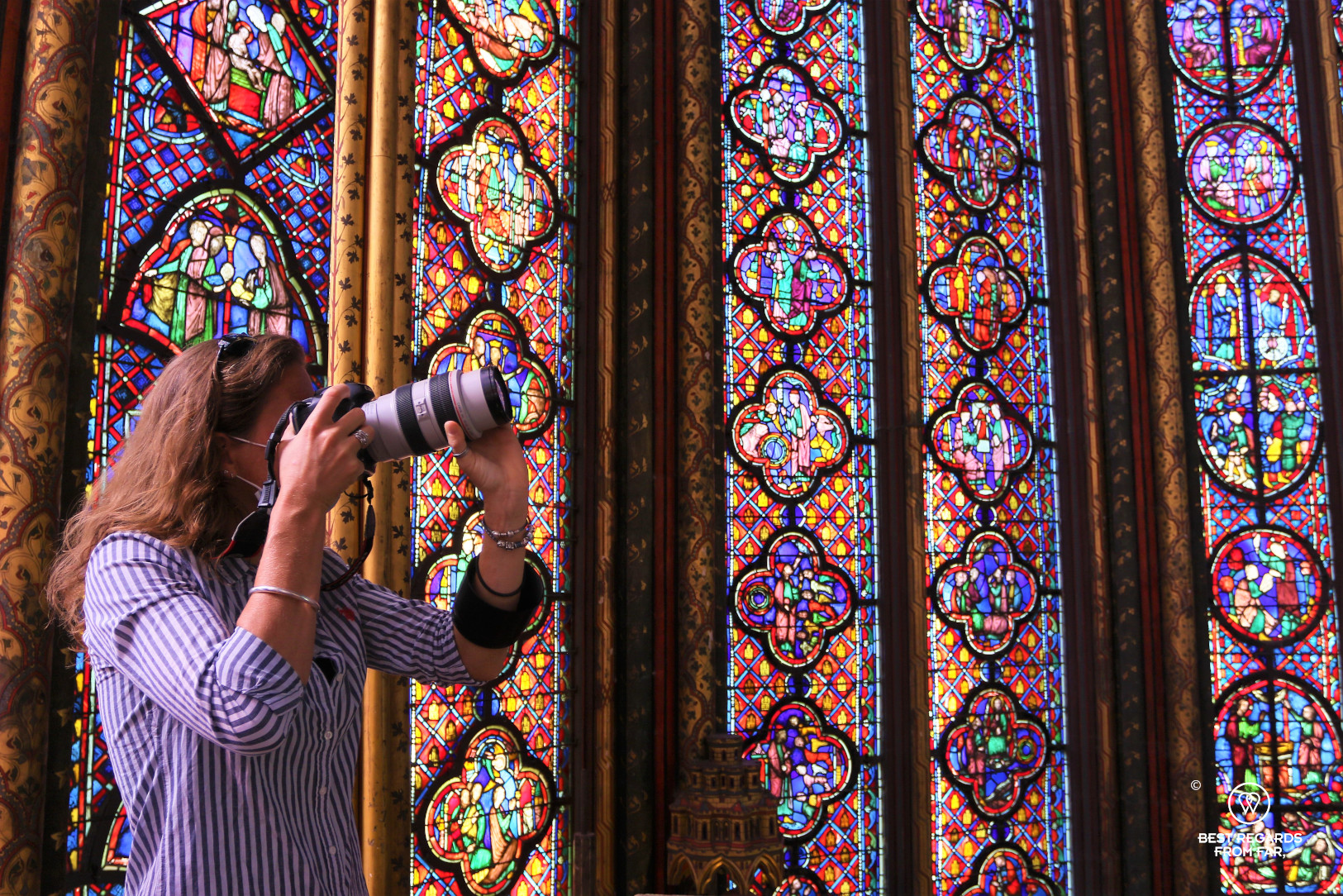 Woman taking a photo of stained-glass windows at La Sainte Chapelle in Paris, France