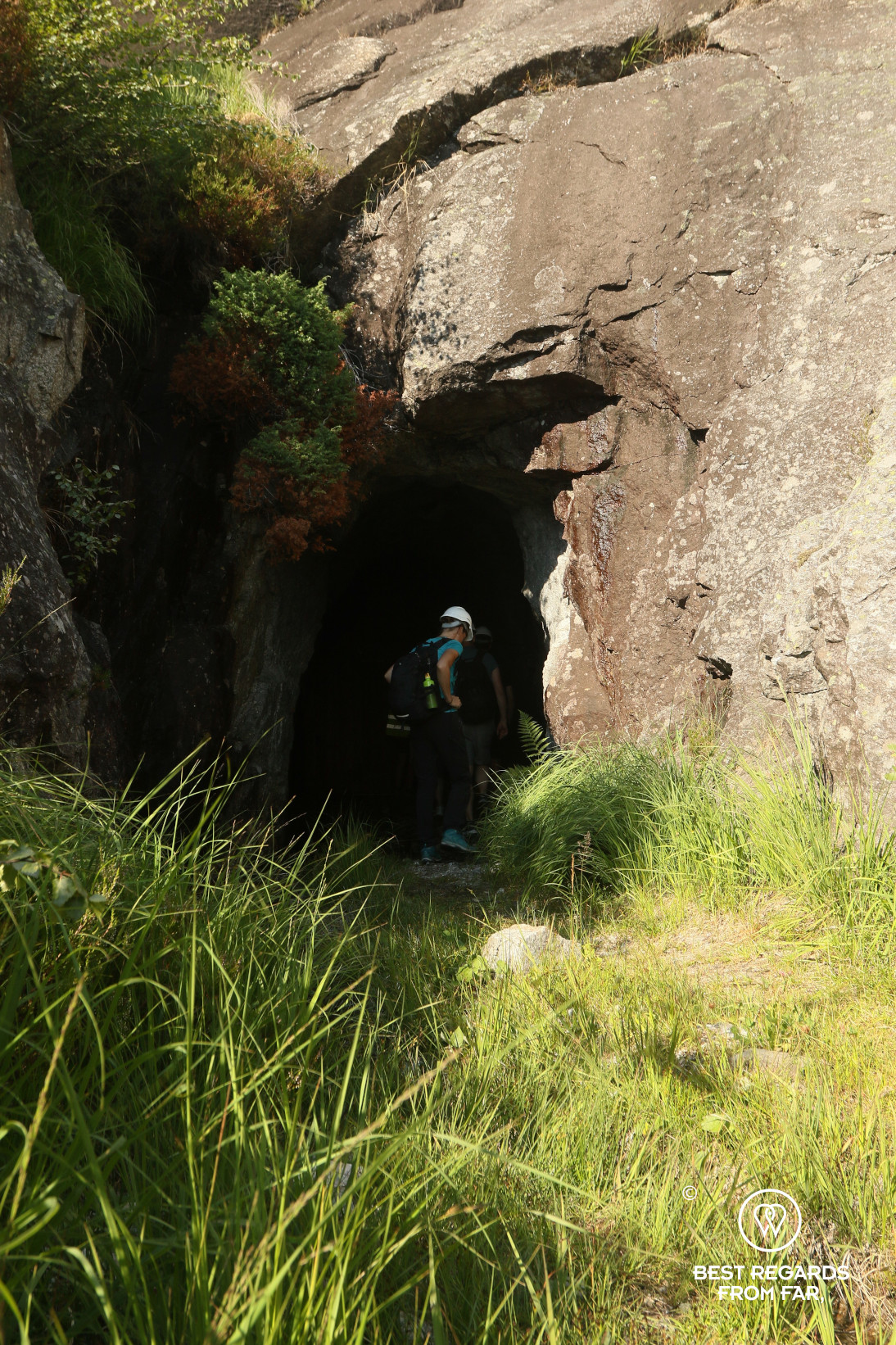 Woman wearing a helmet entering a cave in the mountains