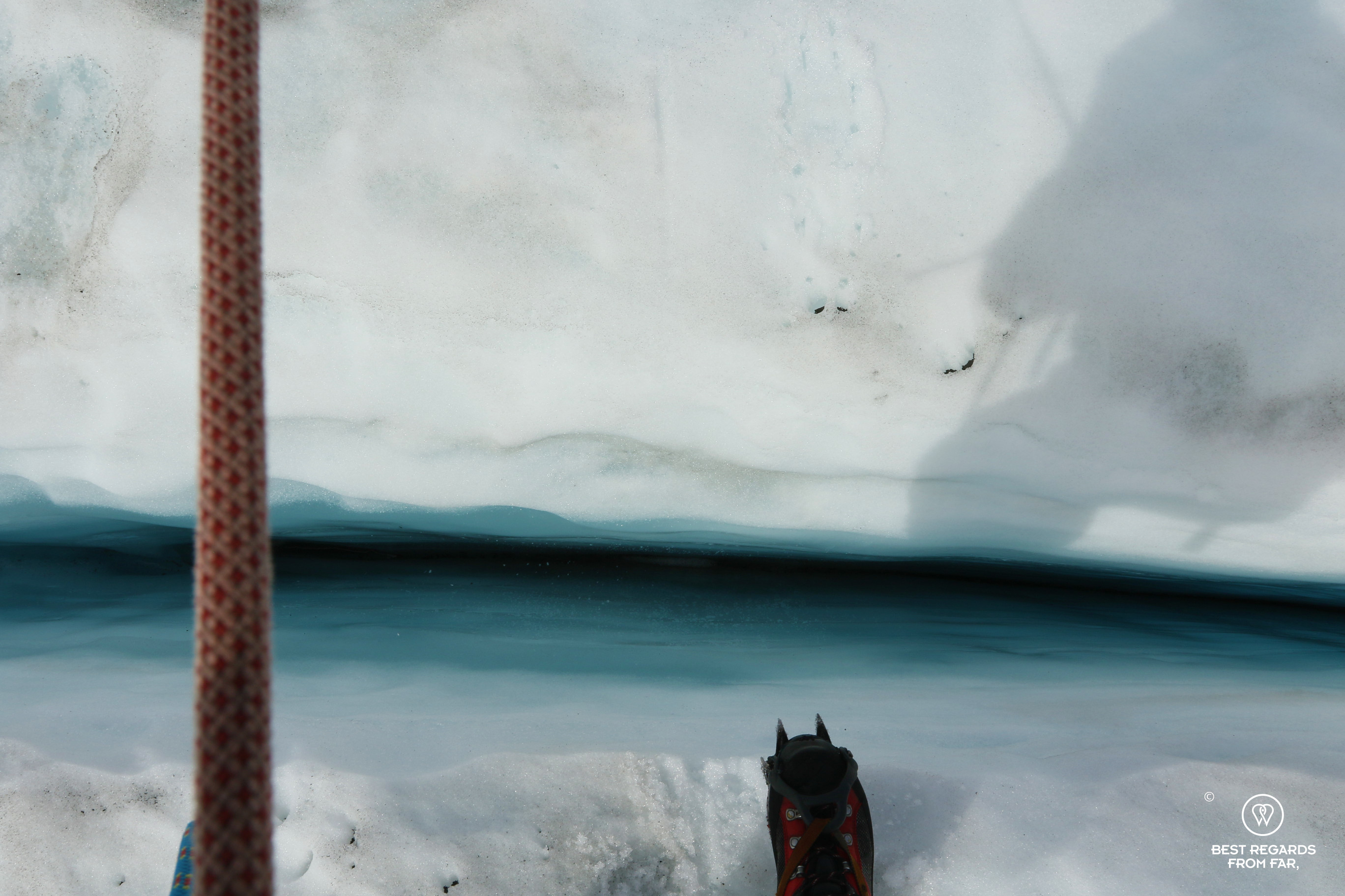 Shoe with crampon about to cross a crevasse of the glacier