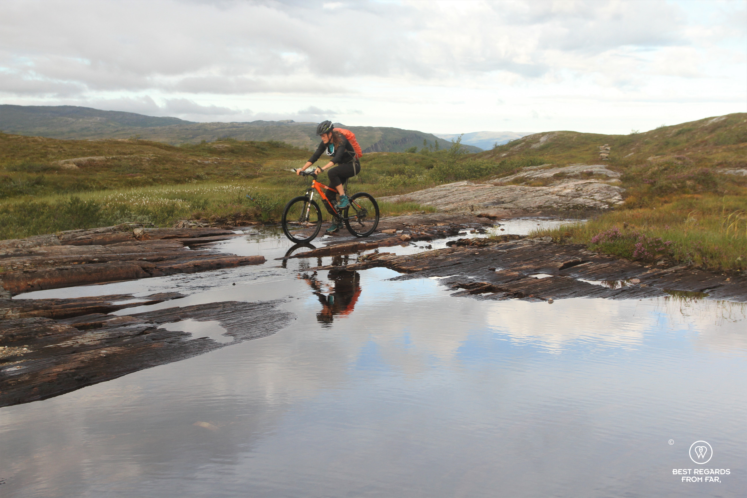 Reflection of a mountain biker in a Norwegian mountain lake