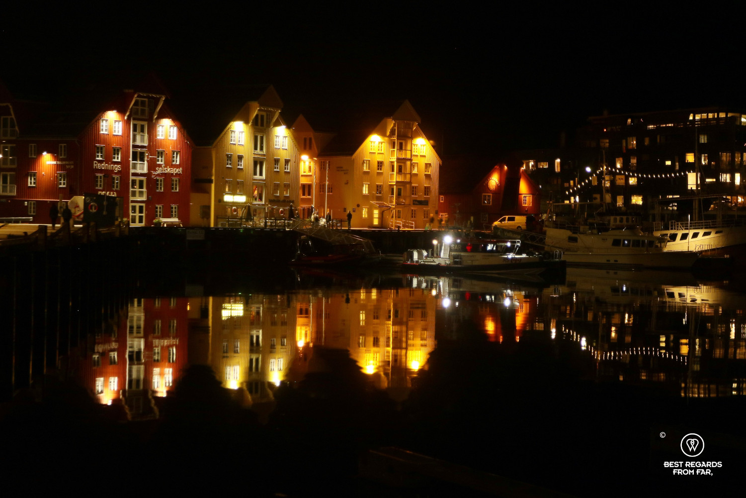 Bryggen in Tromso by night with reflections in the water