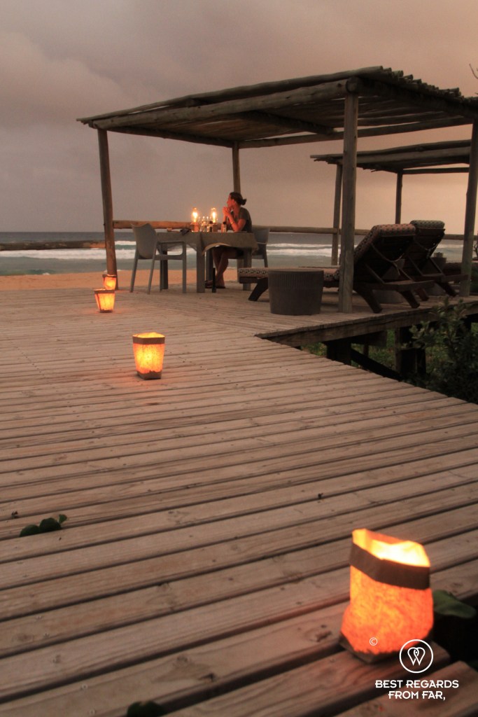 Woman sitting at a table at dusk by the ocean