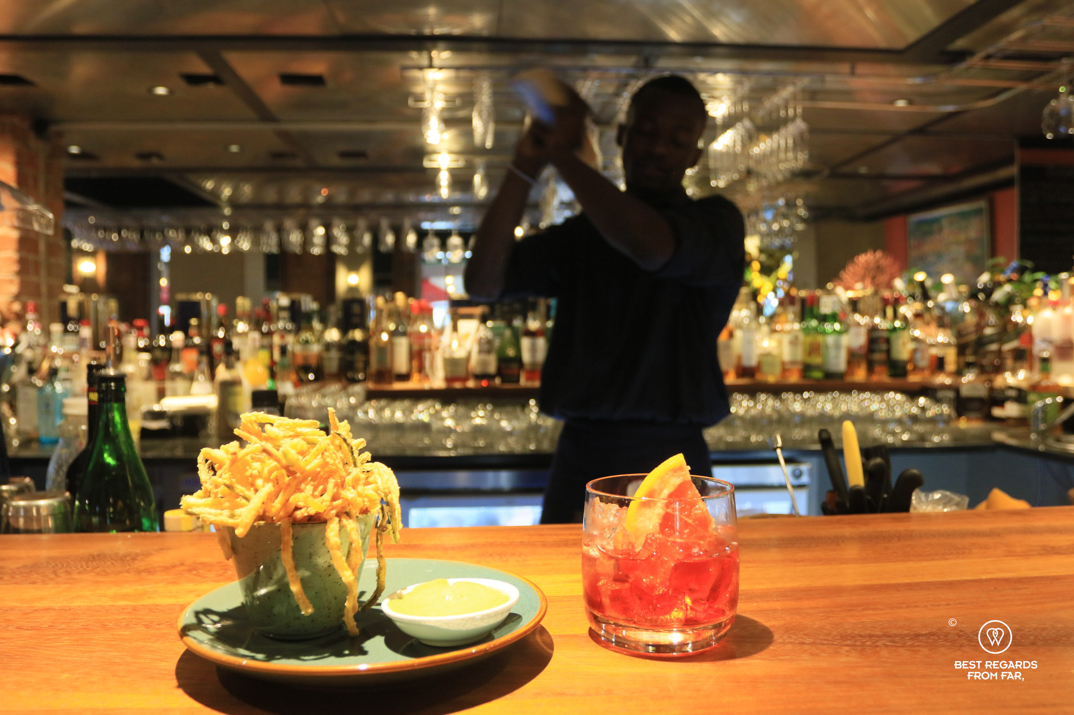 Barman shaking a cocktail with a Negroni in the foreground at Bellagio in Cape Town.