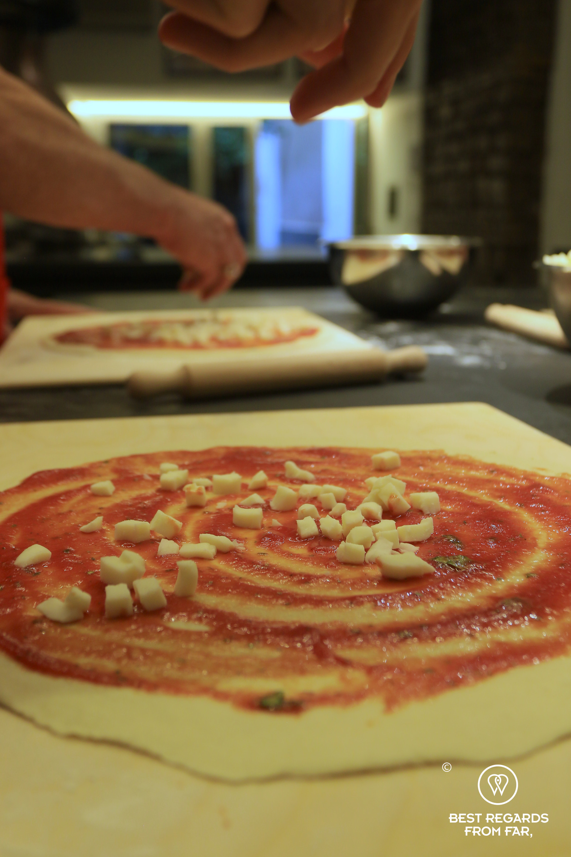 Adding mozzarella on the pizza during a pizza making class