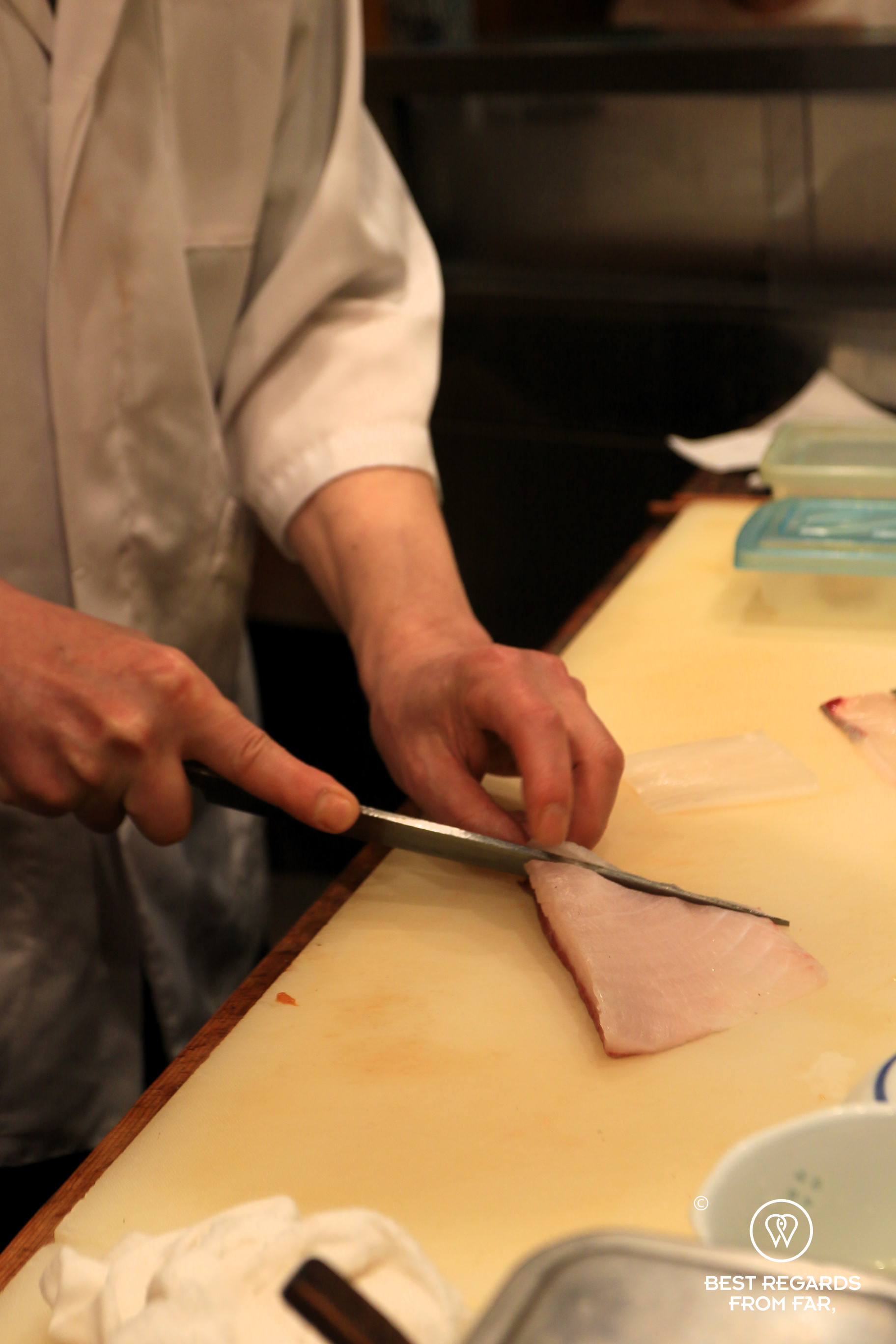 Sushi chef slicing fish