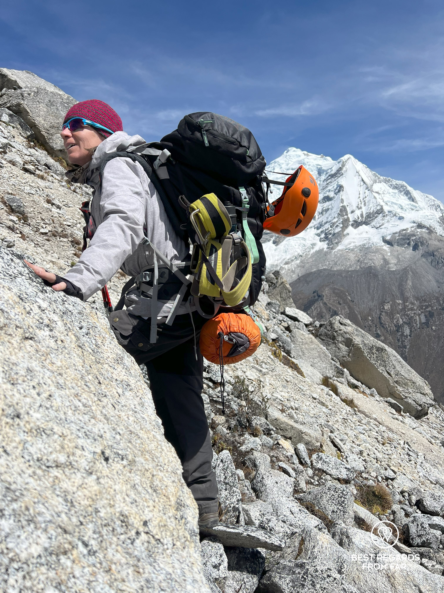 Woman scrambling up granite boulders in the Cordillera Blanca, Peru