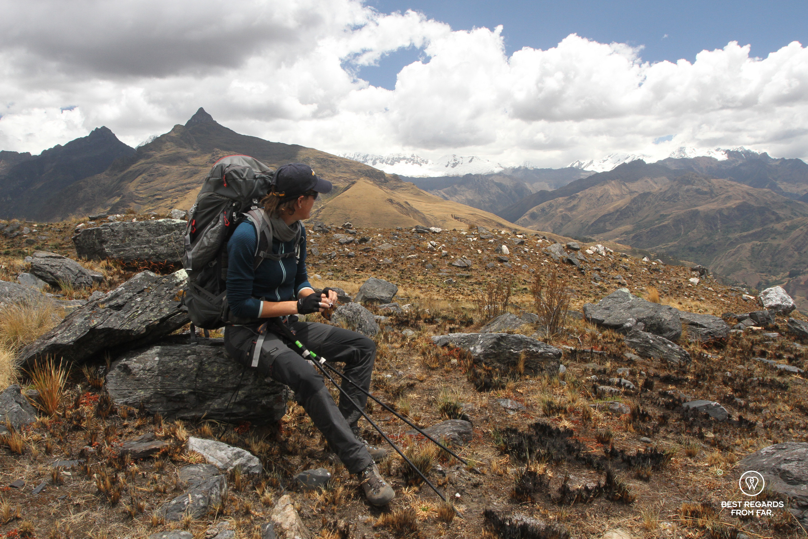 Woman with backpack resting on a rock while trekking the Cordillera Blanca, Peru