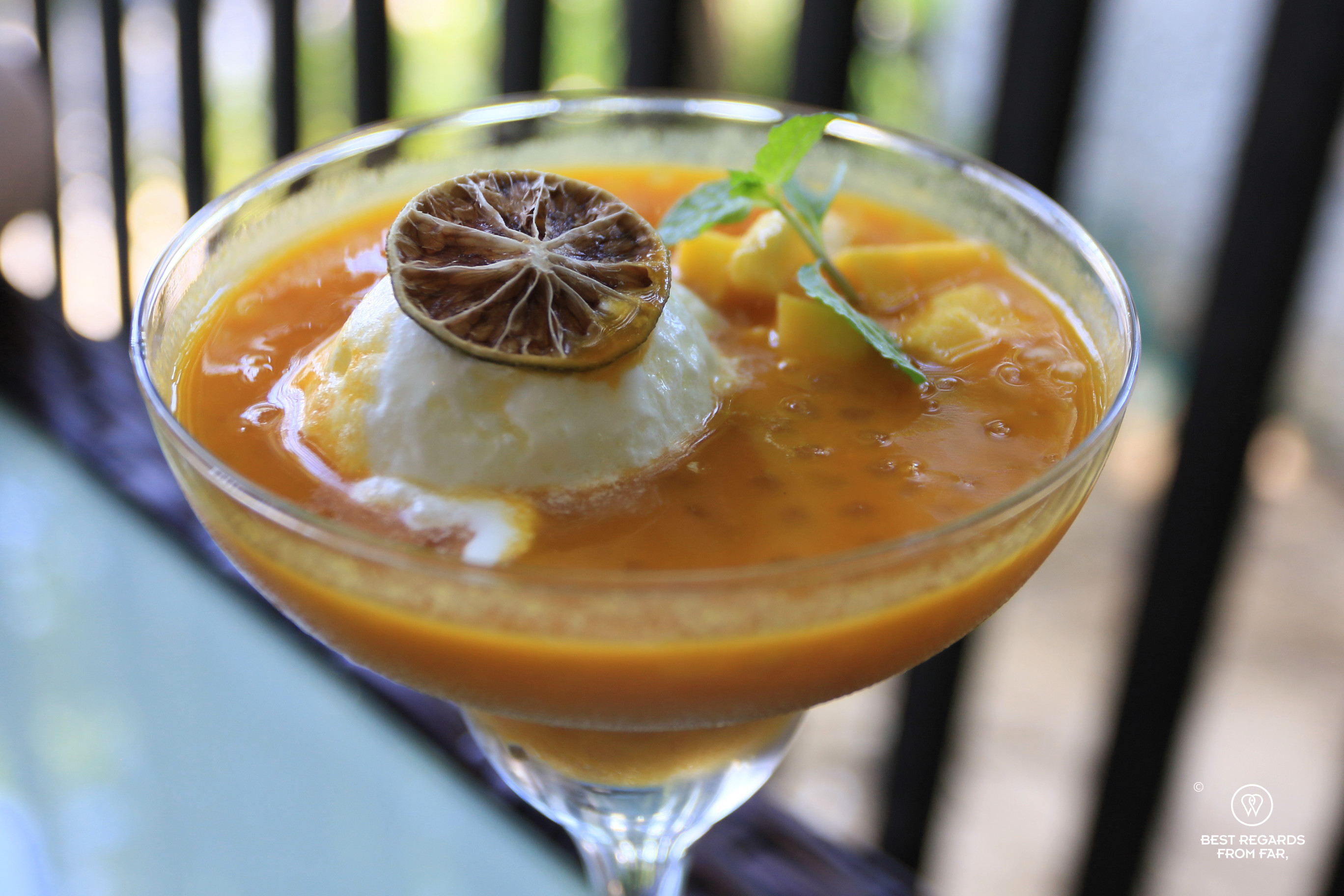 Yellow mango sago desert served in cocktail glass with a scoop of ice cream.