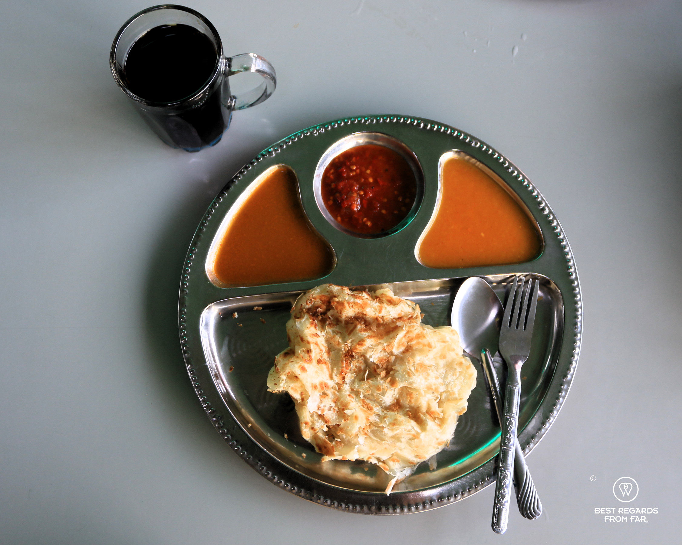 Roti canai served with lentil dahl and two different curries and a coffee.