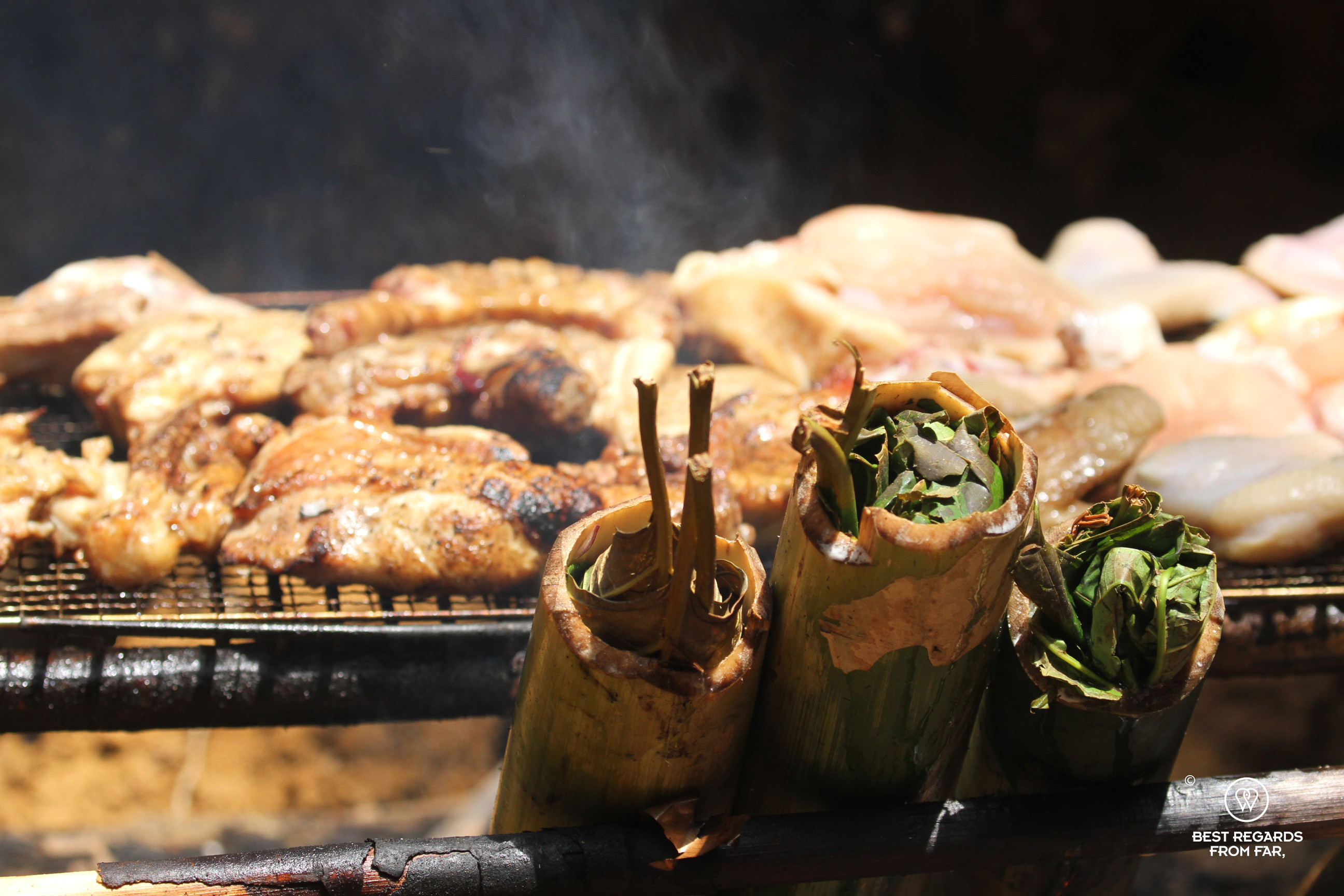 Chicken and pork being grilled on the BBQ with vegetables being cooked in bamboo.