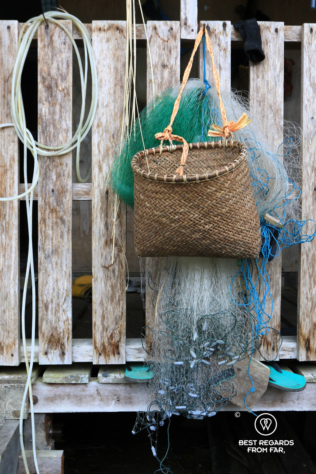 Locally woven basket and fishing nets hung on a wooden structure.