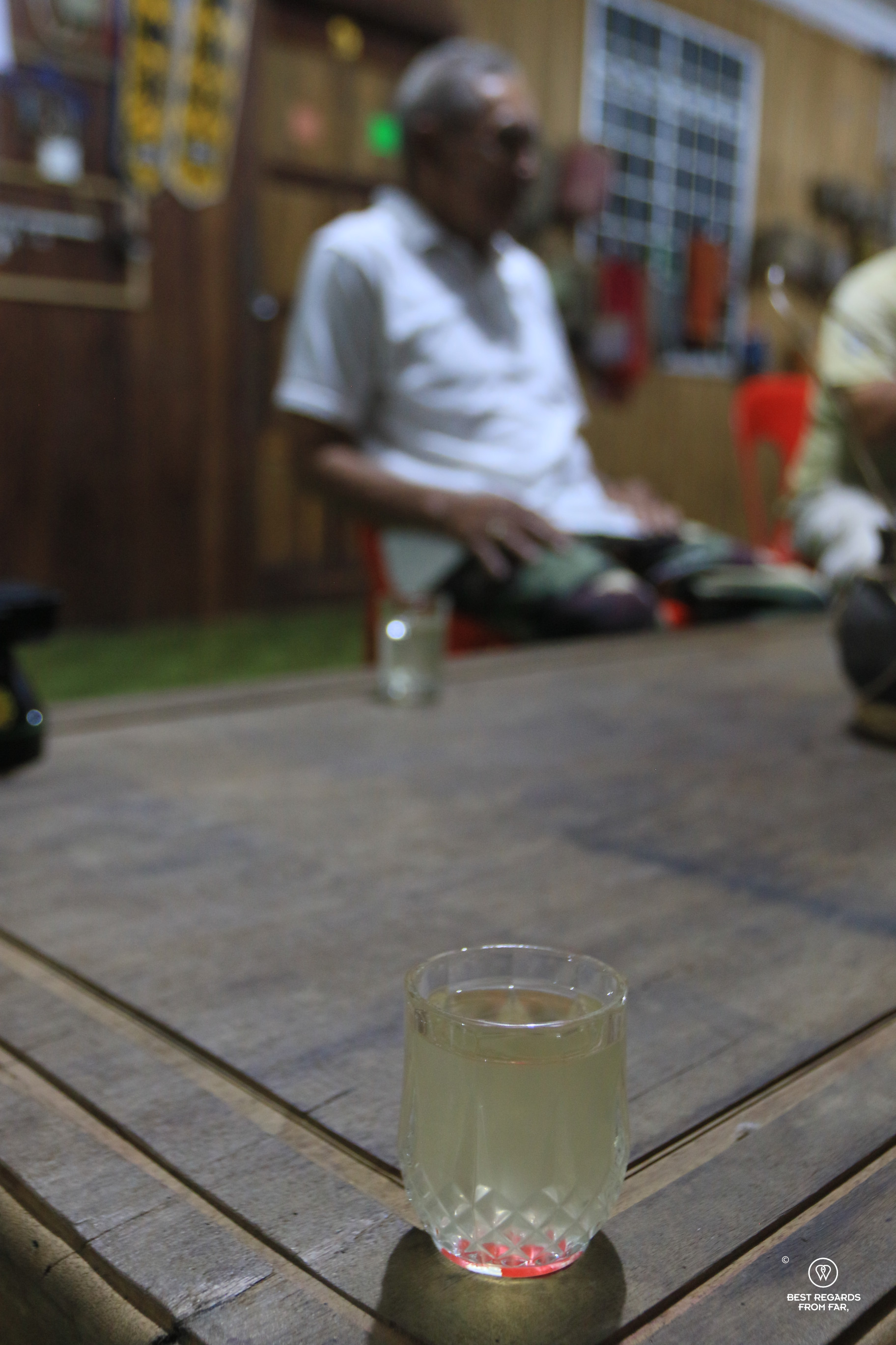 A glass of rice wine on a wooden table in an Iban Longhouse.