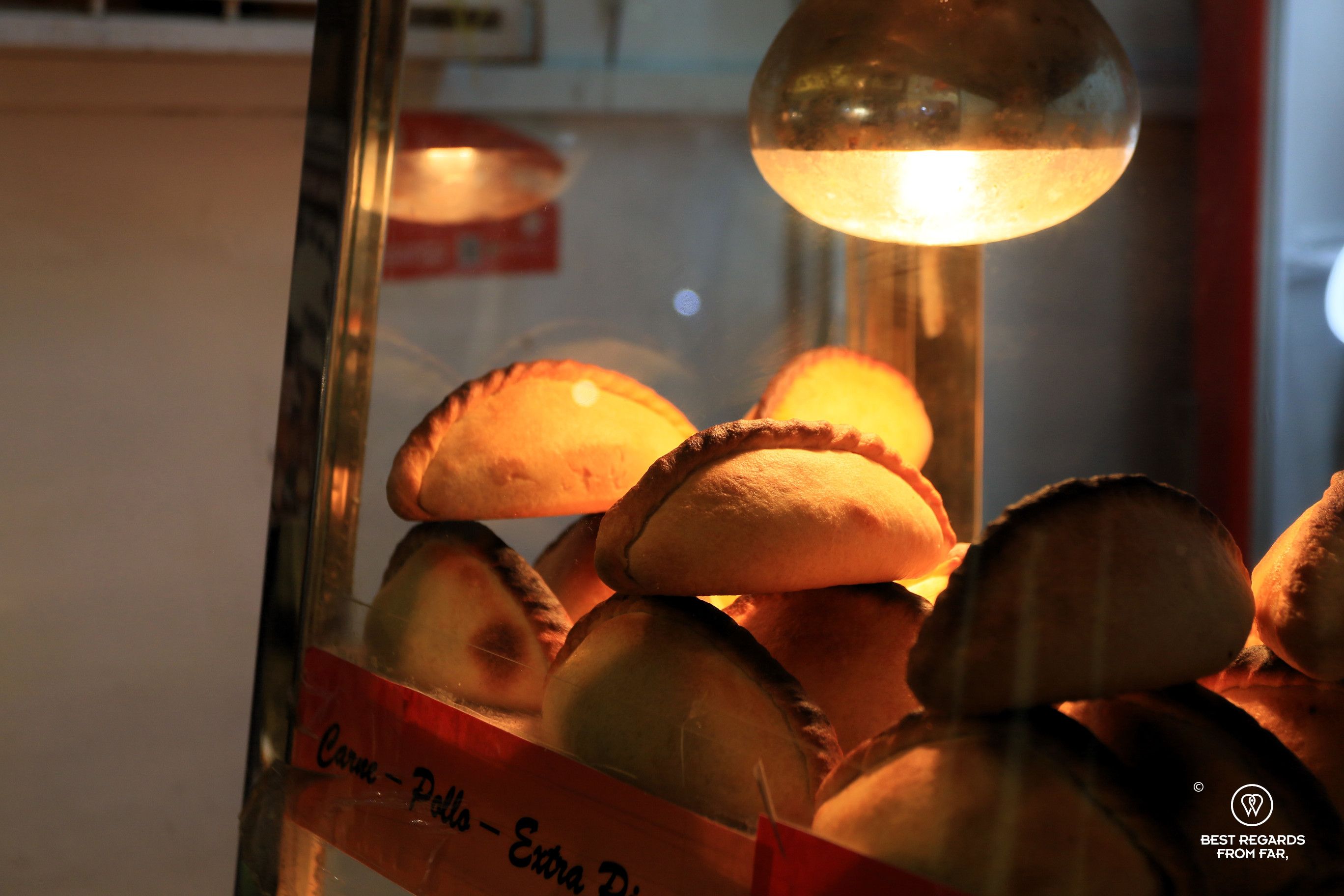 Salteñas street food kept warm under a lamp in Bolivia.