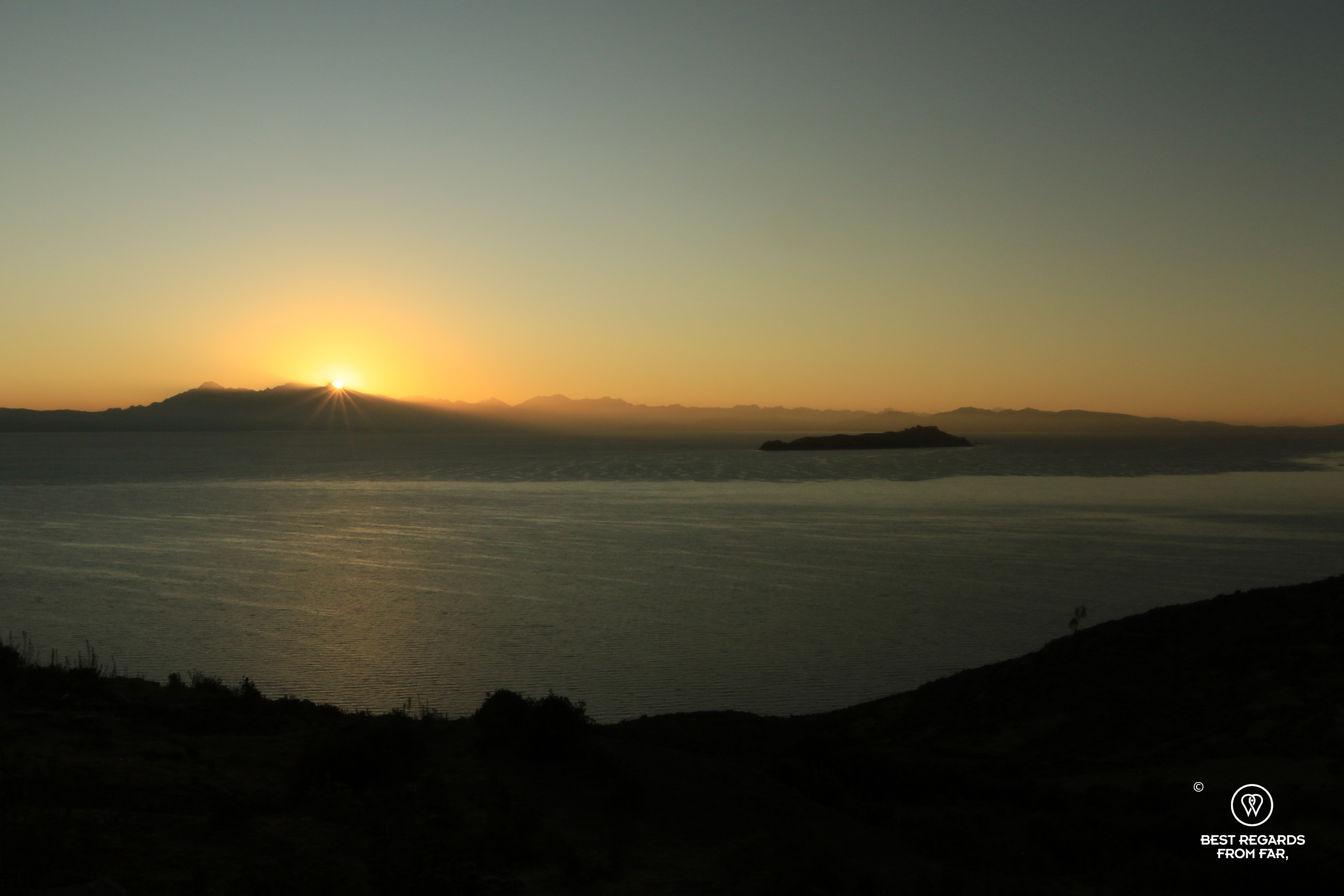 Rays of sun piercing above the mountains at sunrise on Isla del Sol in Bolivia.