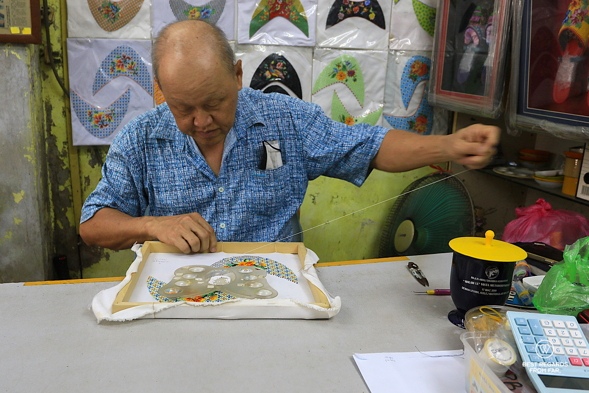Craftsman making a beaded shoe in his small workshop.