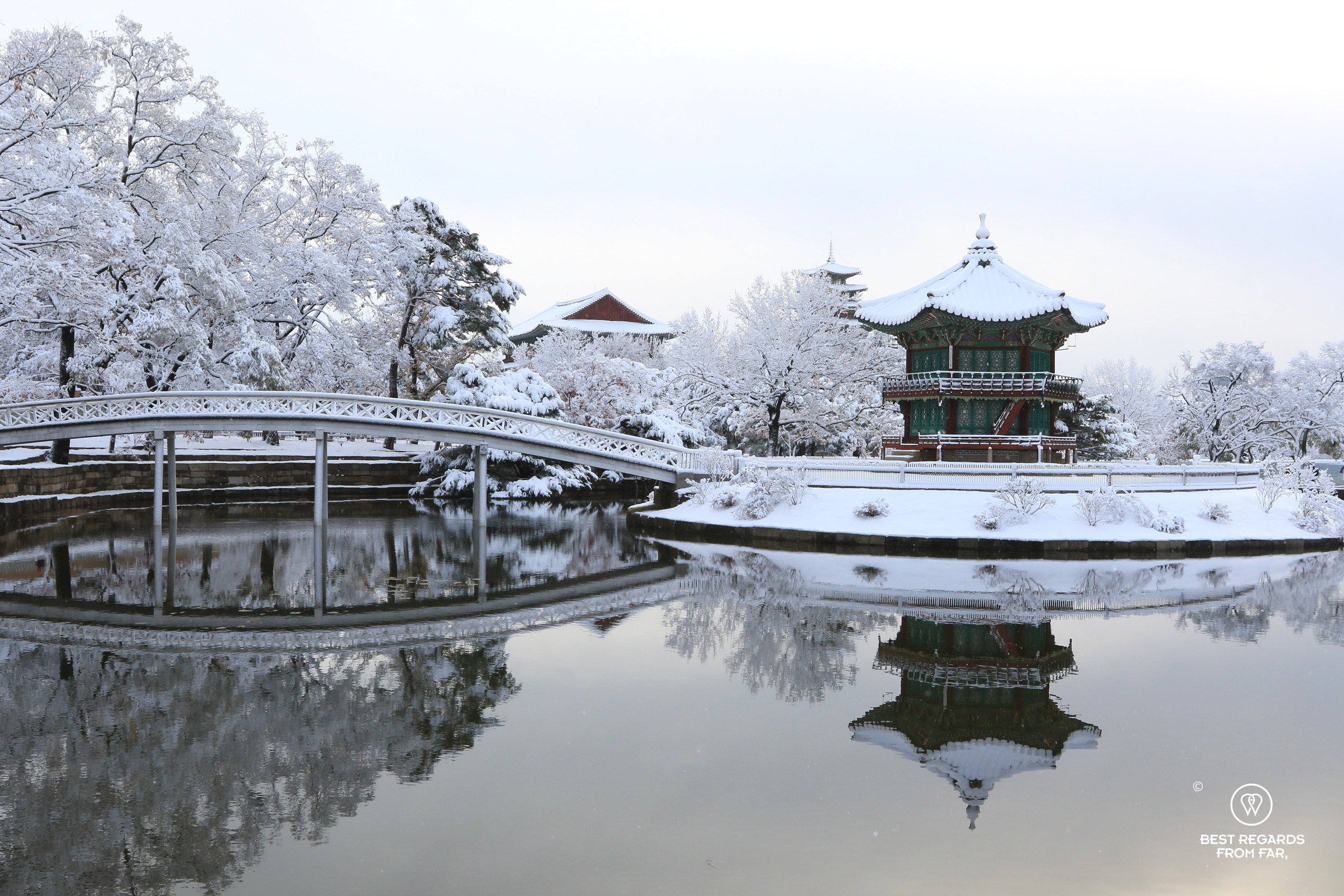 Hyangwonjeong Pavilion and bridge reflecting in the pond on a snow day at Gyeongbokgung Palace.