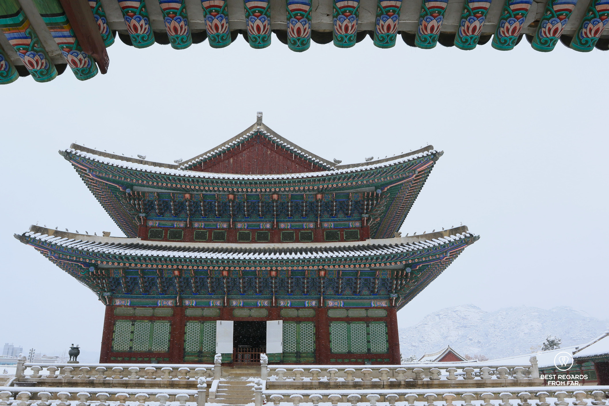 Gyeongbokgung Palace with mountains in the background in the snow in Seoul.