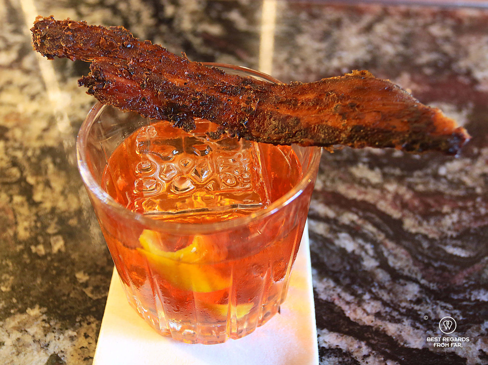 Close up of the bacon old-fashioned cocktail topped off by crispy bacon at B&L in Cape Town.