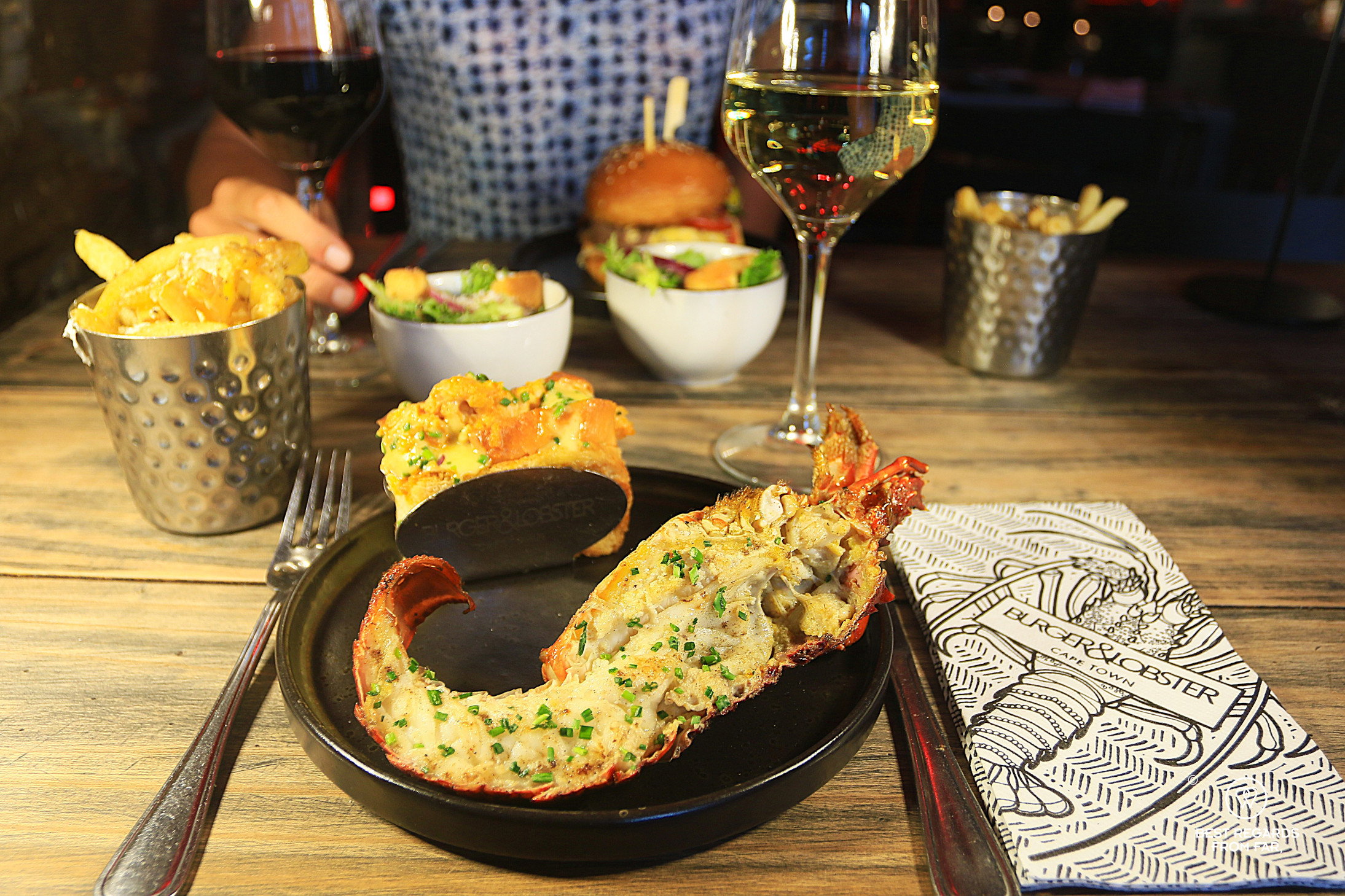 Lobster on a plate with a glass of white wine at B&L in Cape Town.