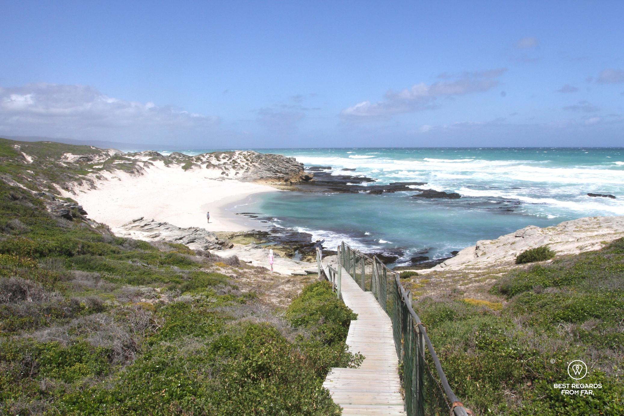 Wooden boardwalk leading to a white sandy beach with turquoise waters of the Indian Ocean at De Hoop Nature Reserve.