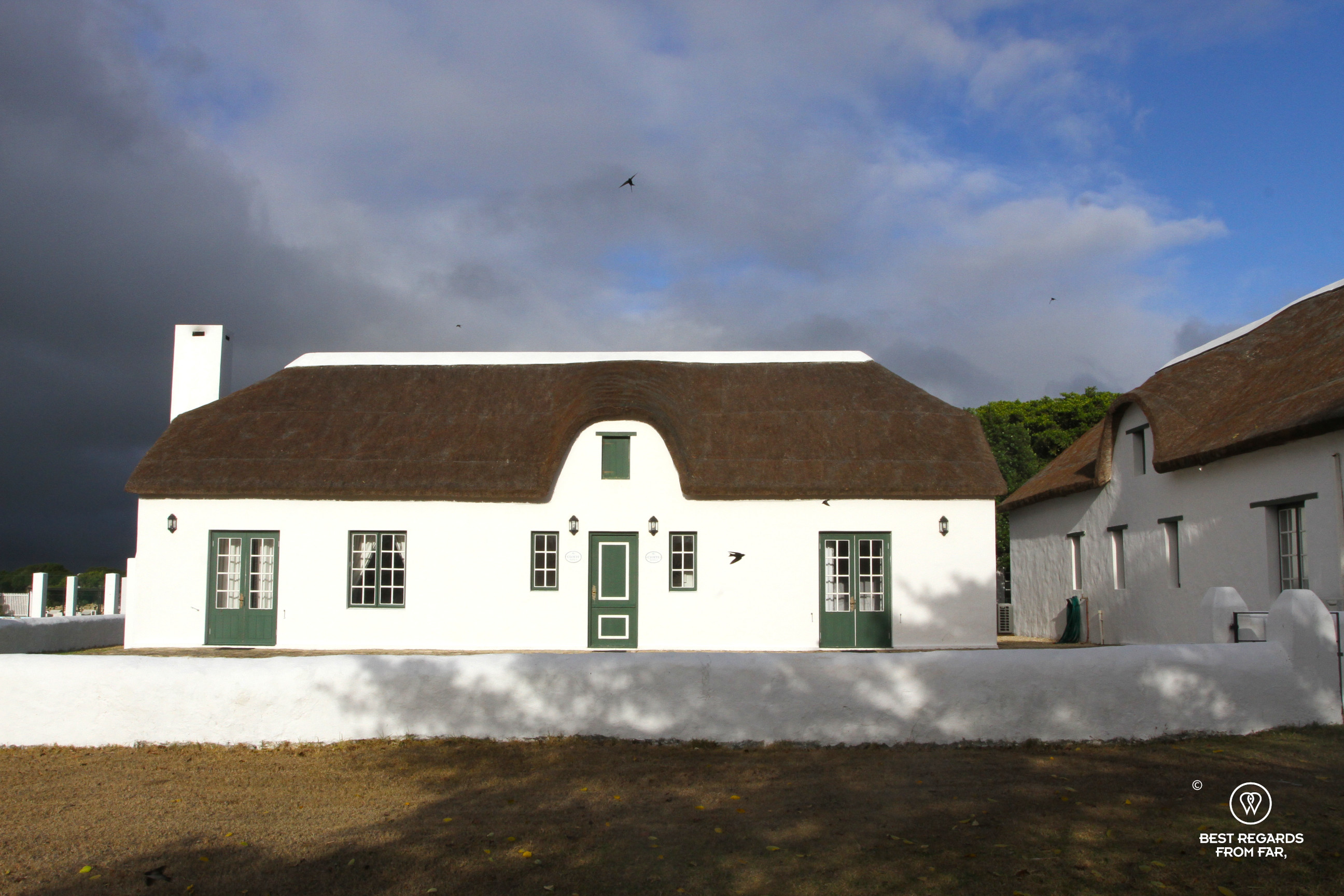 White washed Cape Dutch farm in the sun with its thatched roof.