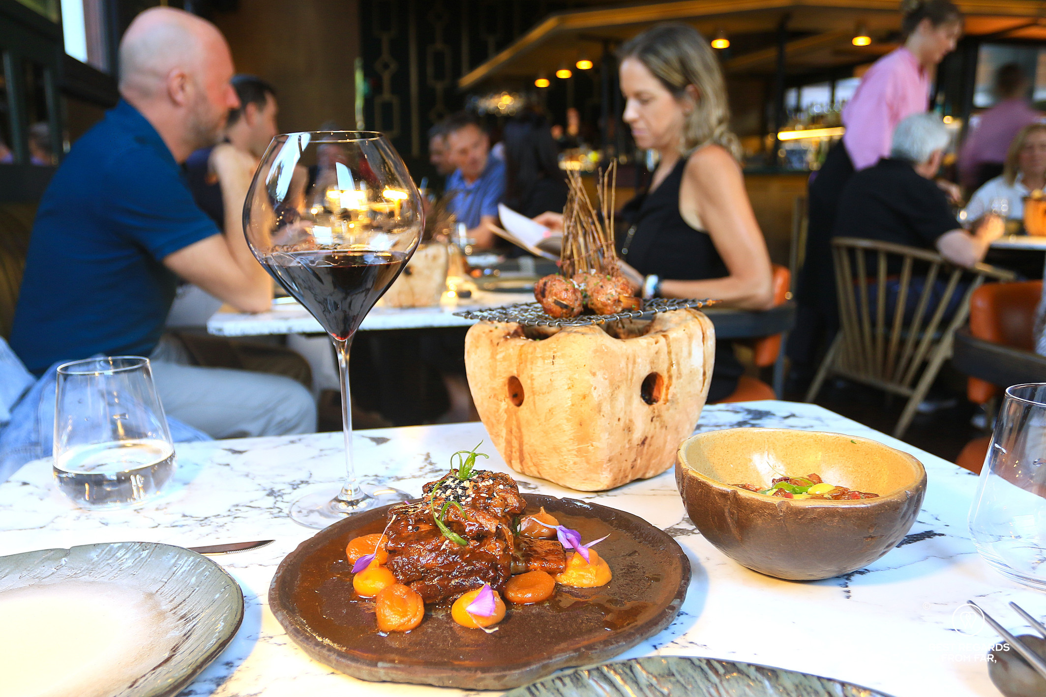 The third course at Nikkei Restaurant in Cape Town with lamb and skewers on a marble table.