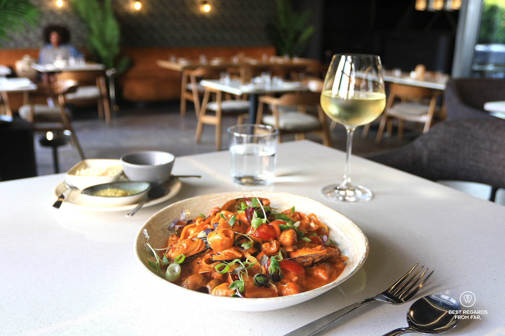 Seafood pasta plate with a glass of white wine at Therapy restaurant in Cape Town.