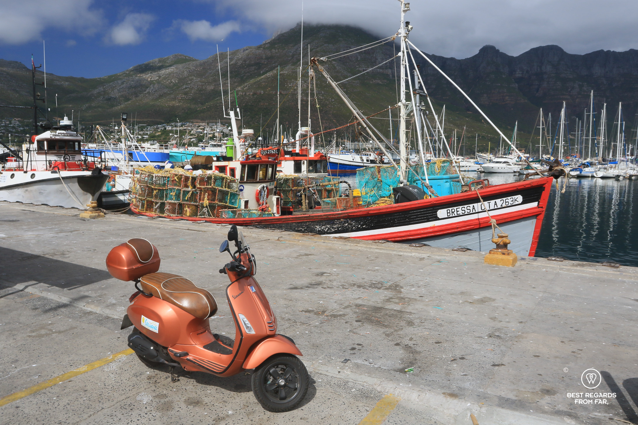 Vespa scooter in front of fishing boats in Houtbay harbour.