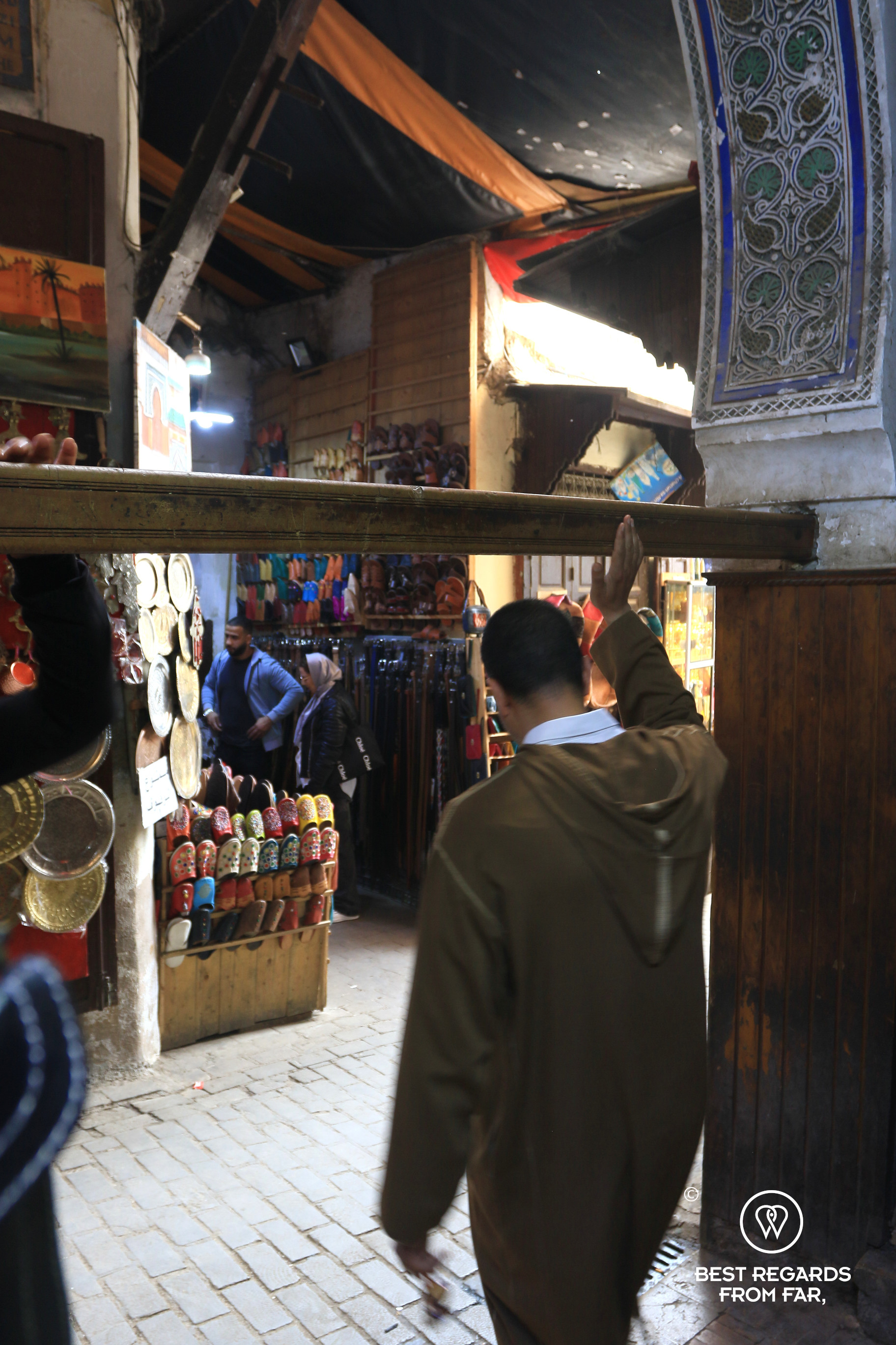 Man passing underneath a wooden beam in the old medina of Fez.