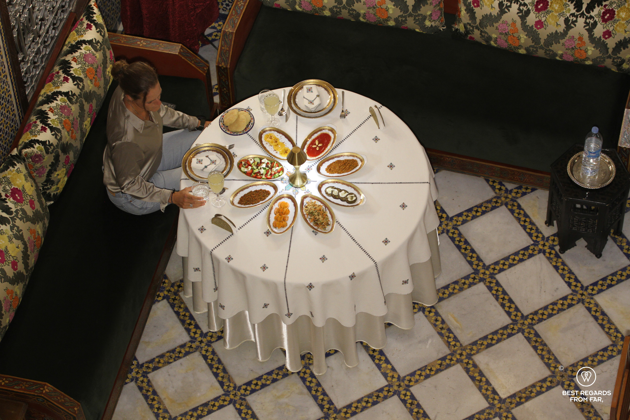 Author Marcella van Alphen seated at a Moroccan dinner table filled with starters.