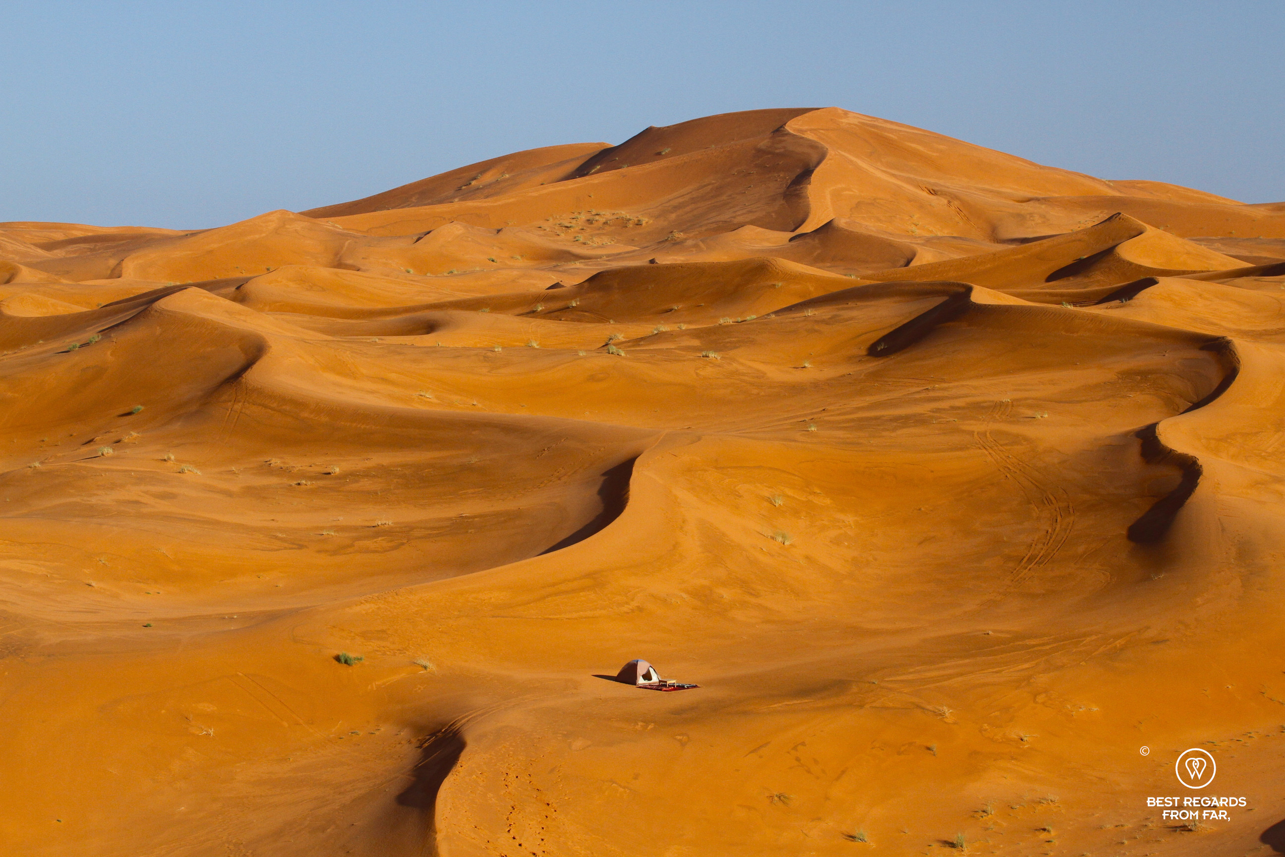 Dome tent amongst the orange dunes of the Sahara Desert.