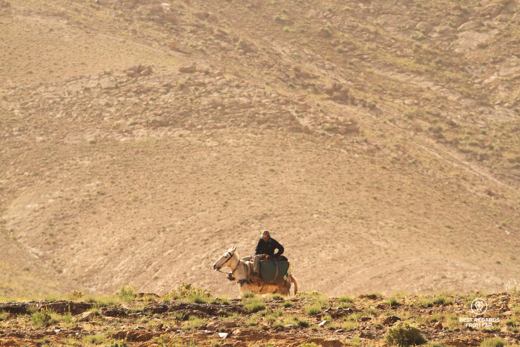 Man riding a donkey in the arid landscapes of the Valley of the Roses.